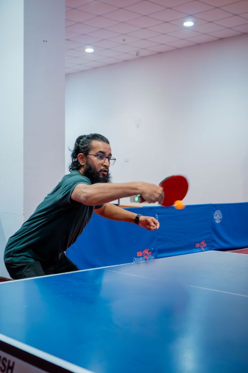 Free A focused player intensely hitting a ping pong ball during a table tennis match indoors. Stock Photo