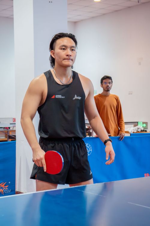 Free Table tennis player focused during an indoor match, holding red paddle before serving. Stock Photo