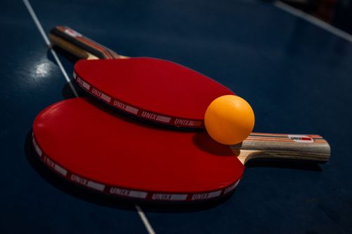 Free Close-up of two red table tennis paddles and yellow ball on a dark blue table. Stock Photo