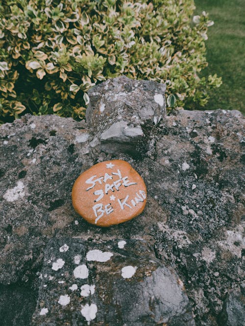 Stay Safe Be Kind text carved on stone in green park during coronavirus pandemic