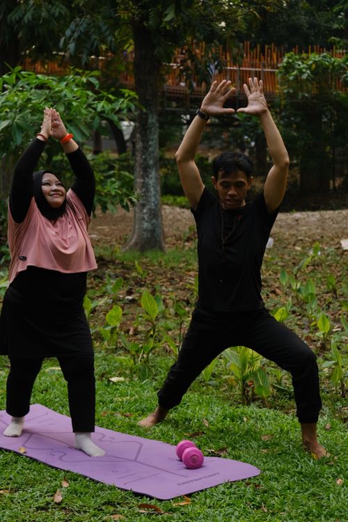 Free Two adults practice yoga outdoors in a Jakarta park, embracing relaxation and mindfulness. Stock Photo
