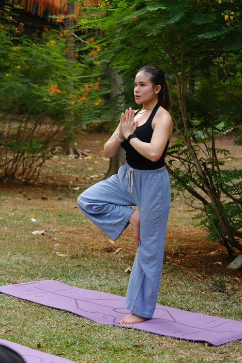 Free An adult woman performing yoga poses on a mat in a lush, green park in Jakarta. Stock Photo