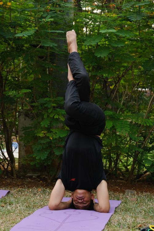 Free Person practicing a headstand on a yoga mat in a Jakarta park, surrounded by greenery. Stock Photo