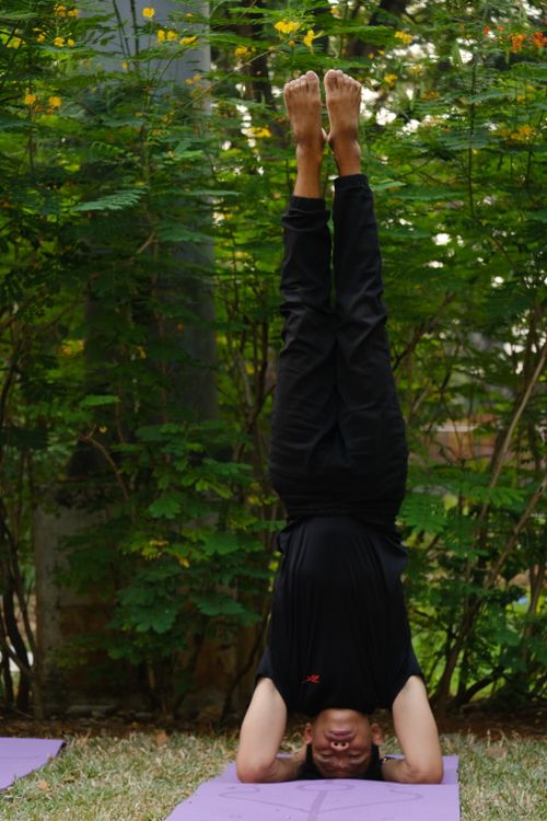Free Adult male performing a headstand yoga pose on a mat outdoors in Jakarta's greenery. Stock Photo