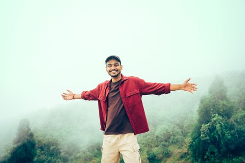 Free Happy man with open arms in a misty mountain landscape, embracing nature's beauty. Stock Photo