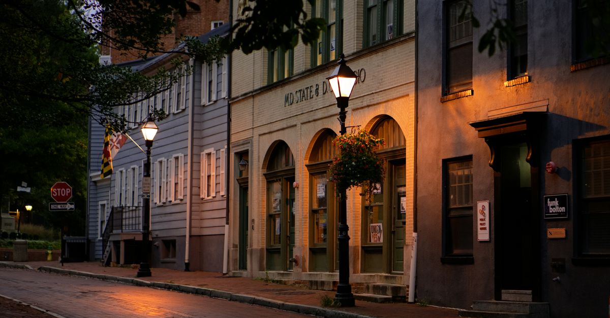 Charming brick-lined street in Annapolis, Maryland captured during twilight with historic buildings and street lamps.
