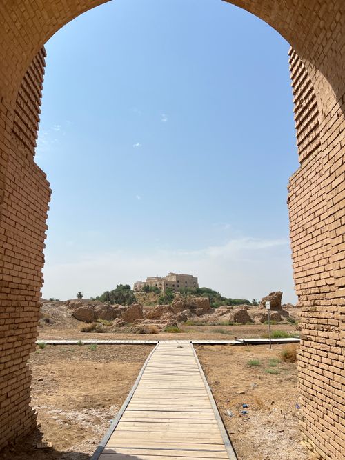 Free View through a historic archway to ancient ruins in Babylon under a clear sky. Stock Photo