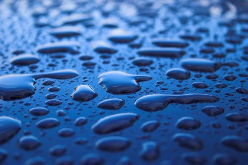 Free Macro photograph showcasing glossy water droplets on a vibrant blue surface. Stock Photo