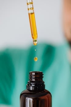 Macro shot of a pipette dispensing liquid into a glass bottle, ideal for medical and scientific themes.