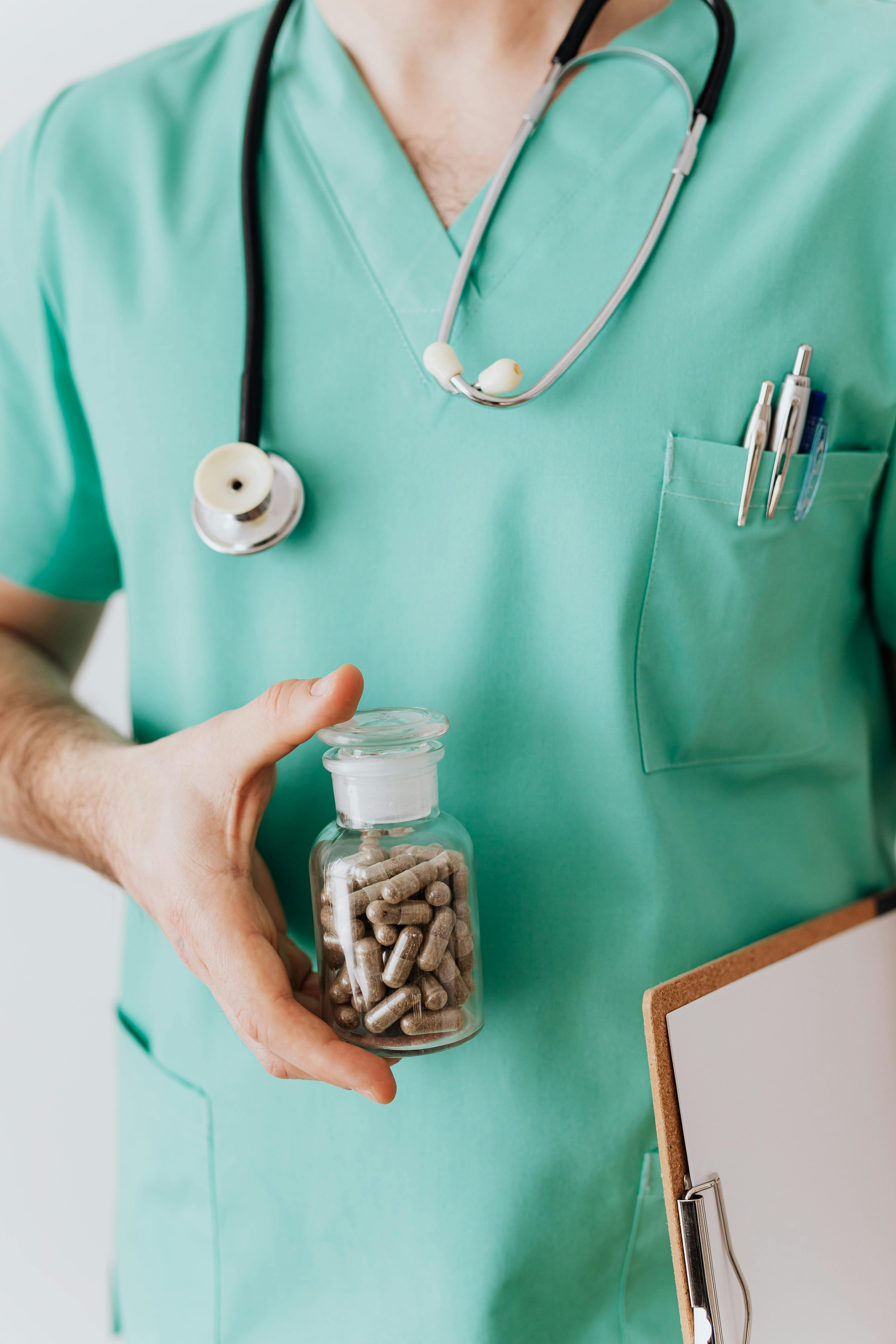 unrecognizable man showing vial with pills for patient