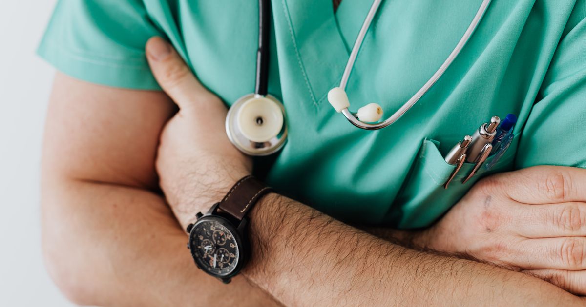 A doctor in scrubs with a stethoscope in a hospital.