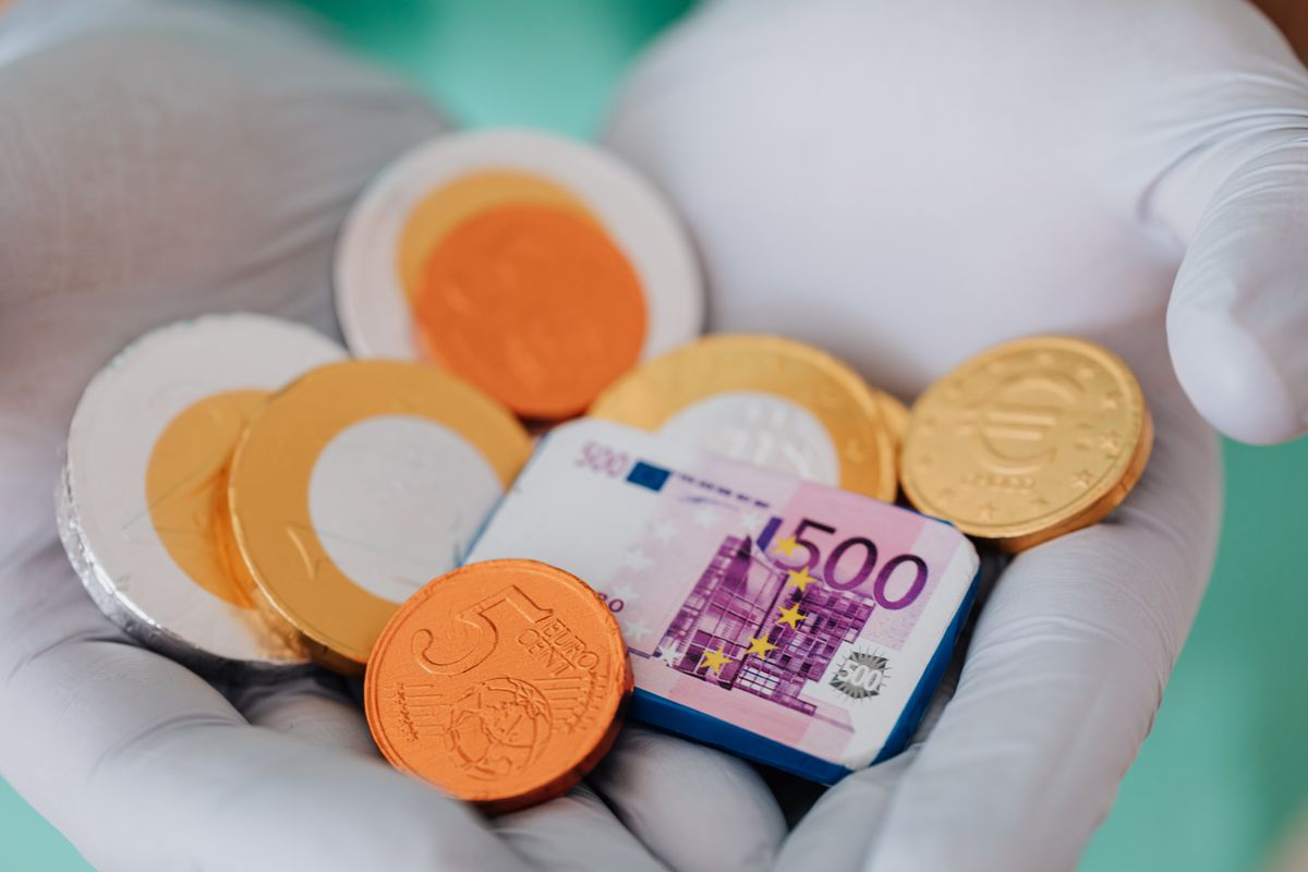 Renkli meyve şekerleri ve altın para yığını masa üzerinde