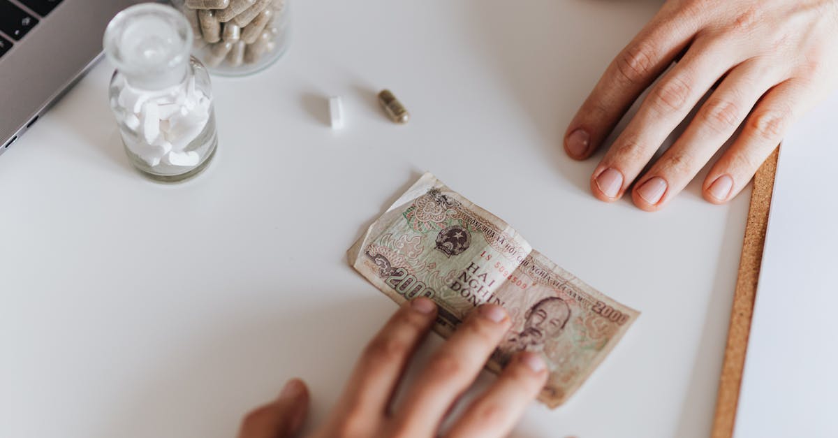 Photo by Karolina Grabowska www.kaboompics.com Conceptual photo showing hands exchanging medicine and currency on a desk.