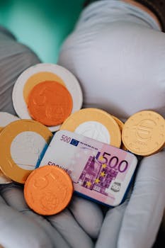 Close-up of gloved hands holding Euro coins and a 500 Euro banknote, showcasing currency concept.