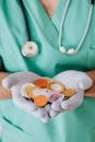 From above crop faceless doctor with stethoscope on shoulders holding in hands chocolate coins