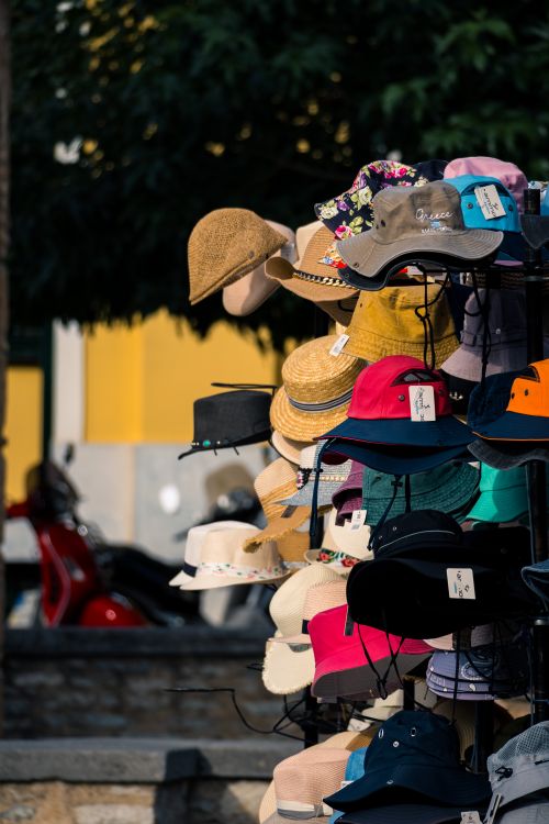 Free A vibrant collection of hats on a stand outdoors, perfect for a sunny day. Stock Photo