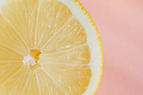 Free Closeup of slice of fresh juicy bright lemon placed on smooth pink surface Stock Photo