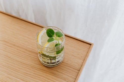 From above faceted thick wall glass of cold exotic drink on wooden desktop