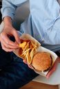 Crop man eating burger and french fries