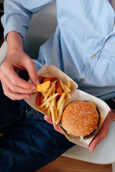 A person enjoys a classic burger and fries meal in a casual setting.
