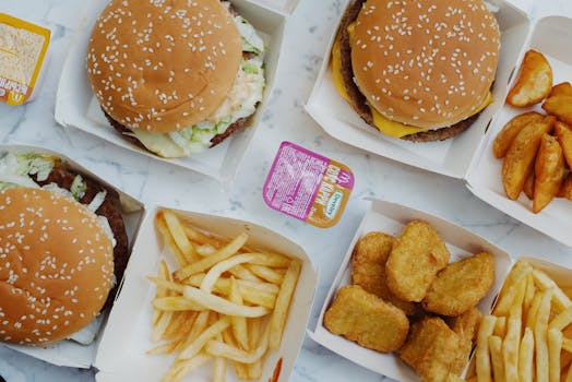 Top view of various fast food items including burgers, fries, and nuggets on a marble table.