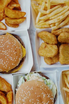 Closeup of delicious junk food consisting of burgers with nuggets and french fries placed on marble table