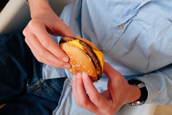 A person taking a bite of a burger — photo by ready made on Pexels