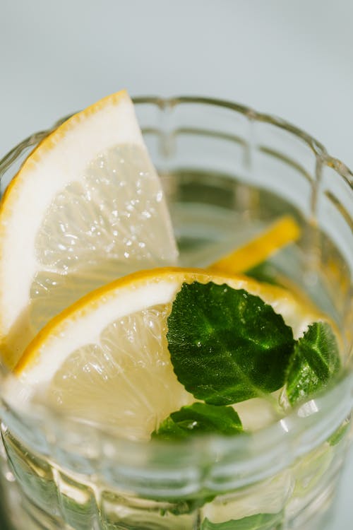 From above of glass of fresh cocktail made of mint leaves and slices of lemon