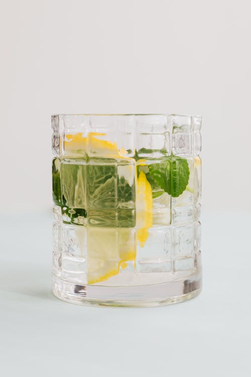 Glass of mojito with lemon and mint on white background