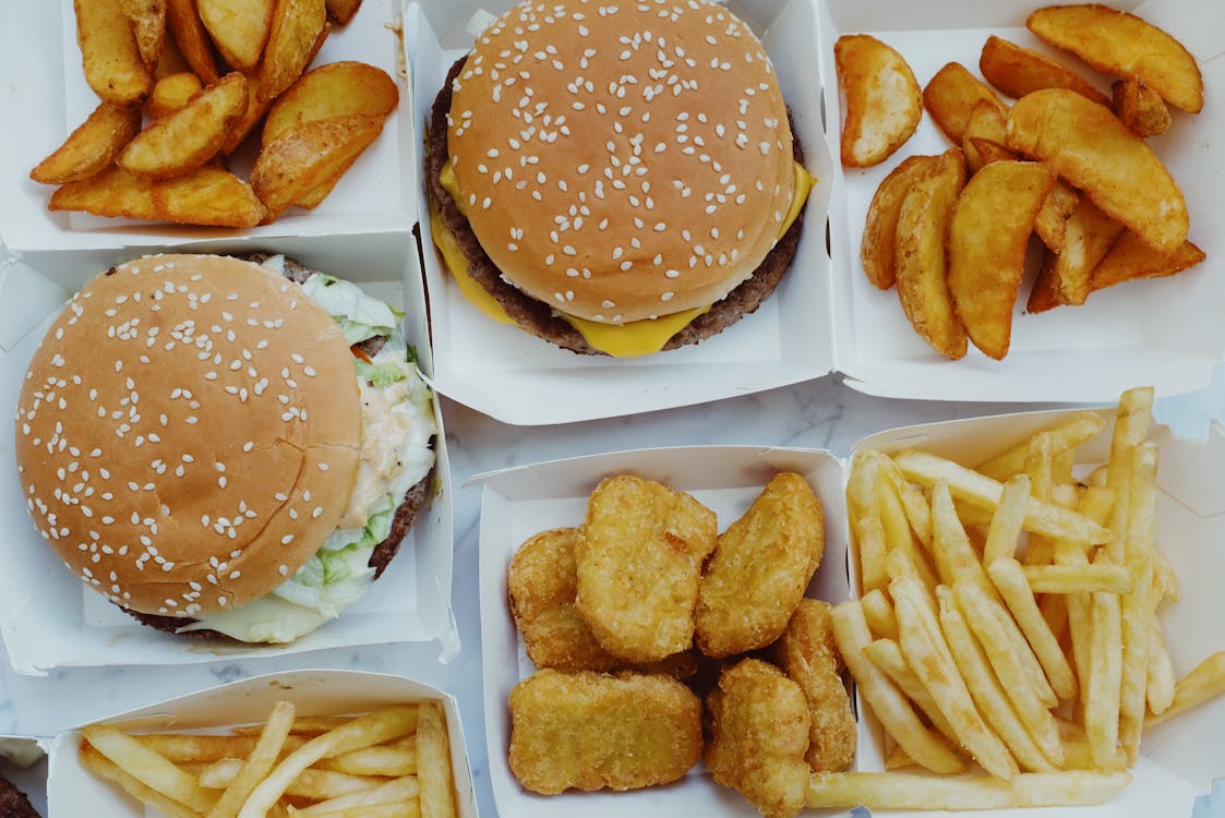 Free Top view of yummy junk food consisting of burgers and french fries with nuggets placed in boxes on marble background Stock Photo