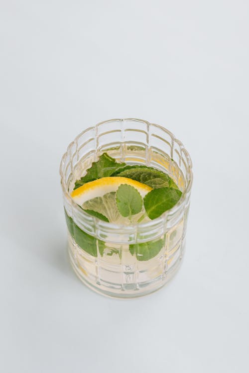 From above of nonalcoholic beverage made of lemon and mint and placed on white background