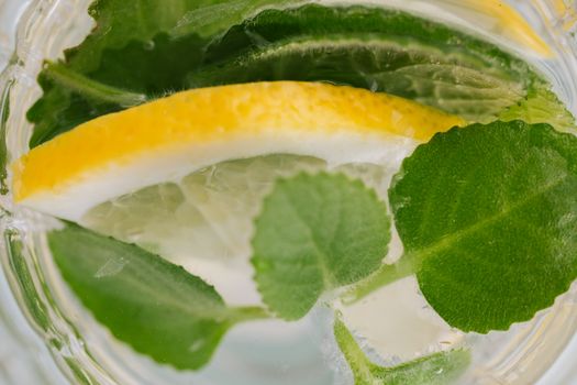 Closeup top view of nonalcoholic drink made of slices of lemon and leaves of mint