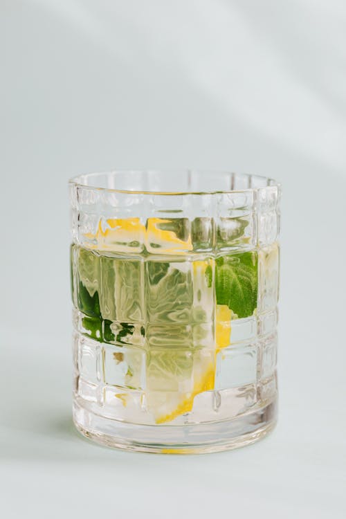 Flat lay of glass of fresh drink with lemon and mint placed on white background