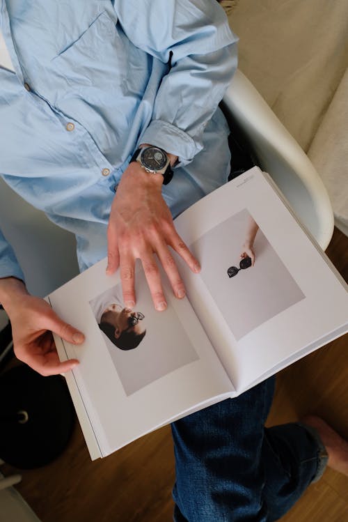 Free Unrecognizable guy with opened magazine at home Stock Photo