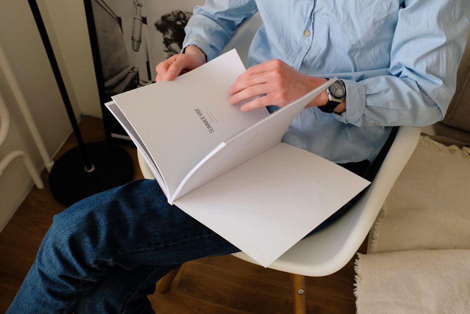 スタイリッシュな椅子に座って雑誌を読む男性、穏やかな午後を室内で楽しむ。