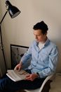 Serious young man reading magazine at home