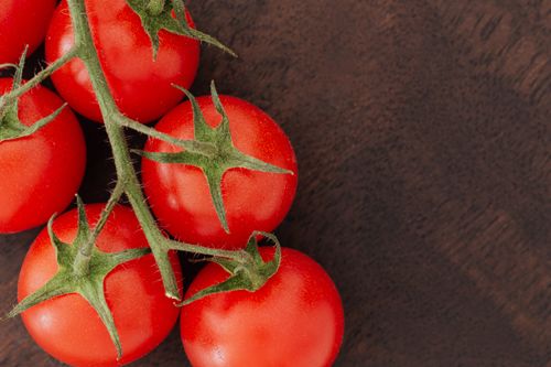 Free From above of culled branch of red ripe tomatoes placed on wooden table Stock Photo