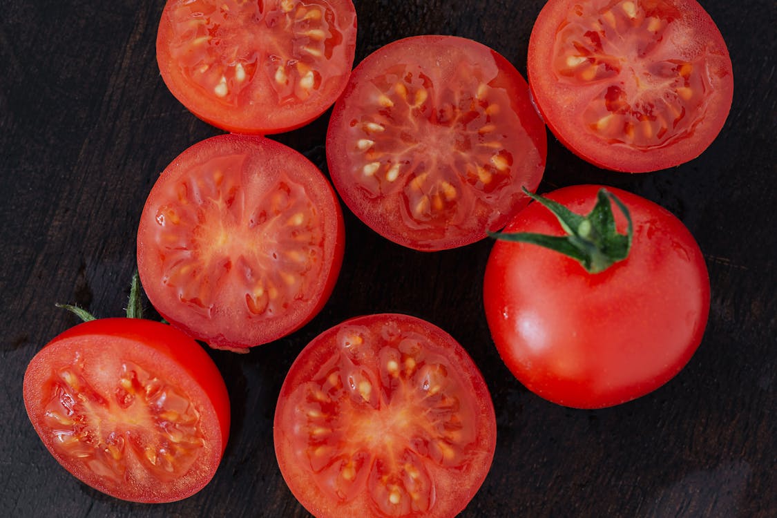 Free Halves of tomatoes and whole tomato on cutting board Stock Photo