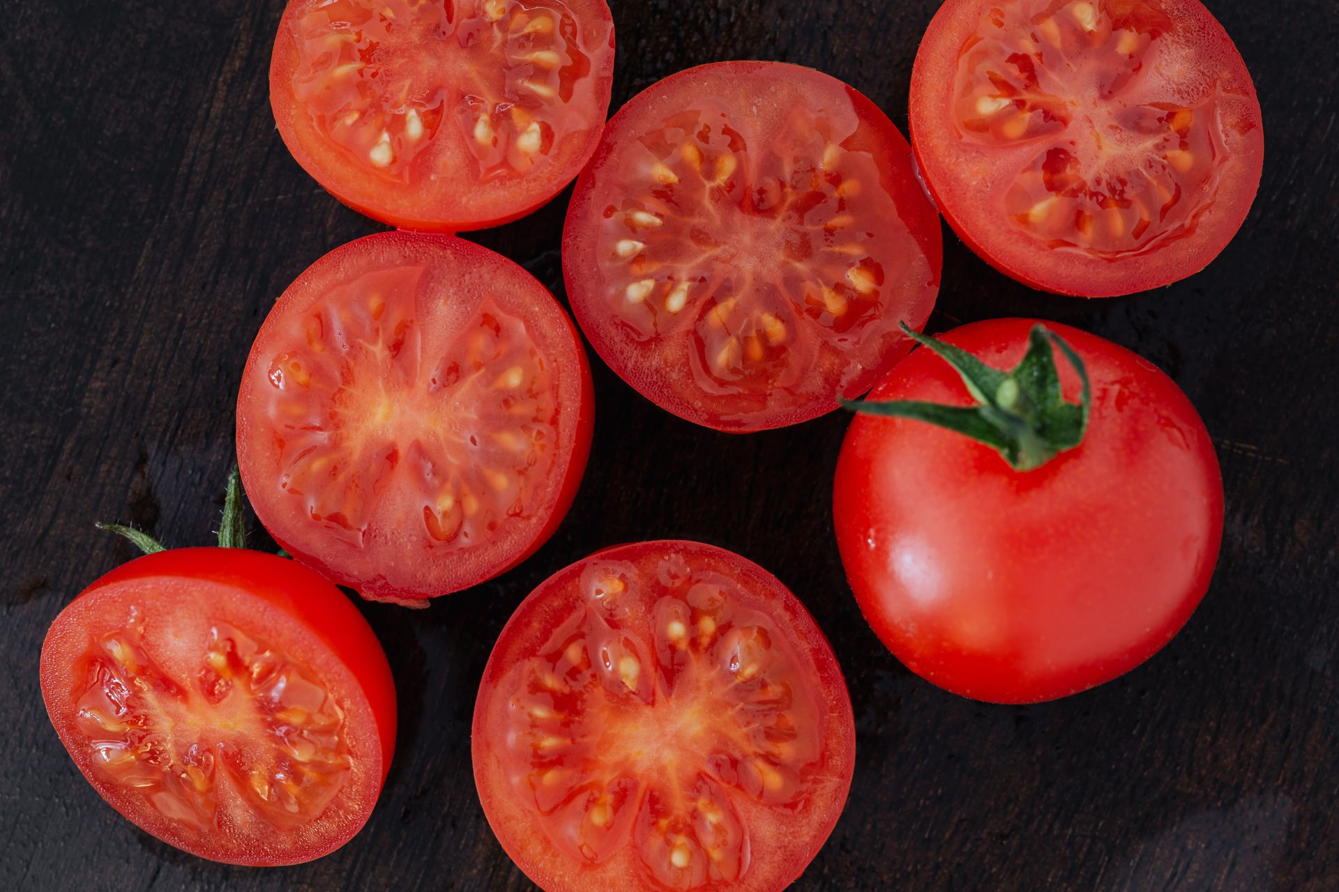 Halves of tomatoes and whole tomato on cutting board