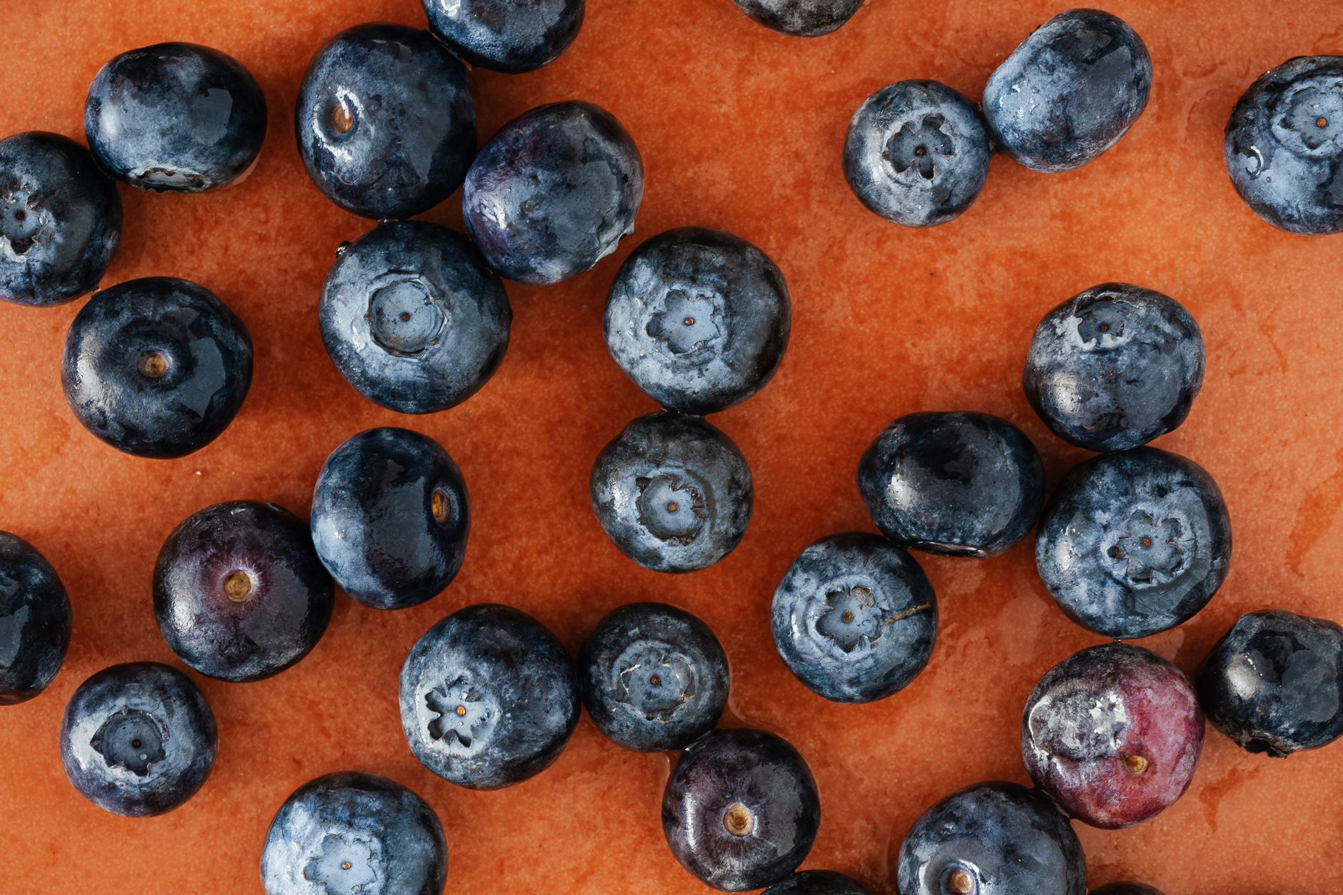 Stack of gooey vegan lemon blueberry bars on a plate with fresh blueberries