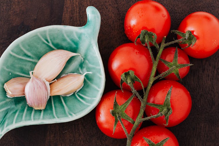 Tomatoes And Plate Of Cloves On Table