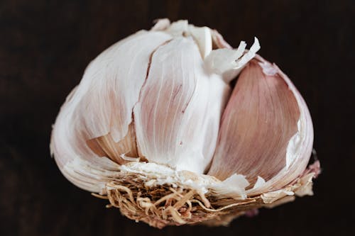 Free Top view of fresh halved garlic in peel placed on dark brown surface before training in restaurant Stock Photo