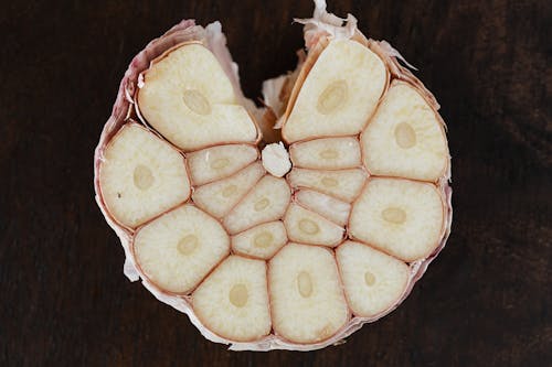 Bulb of ripe garlic in peel cut in half on wooden board