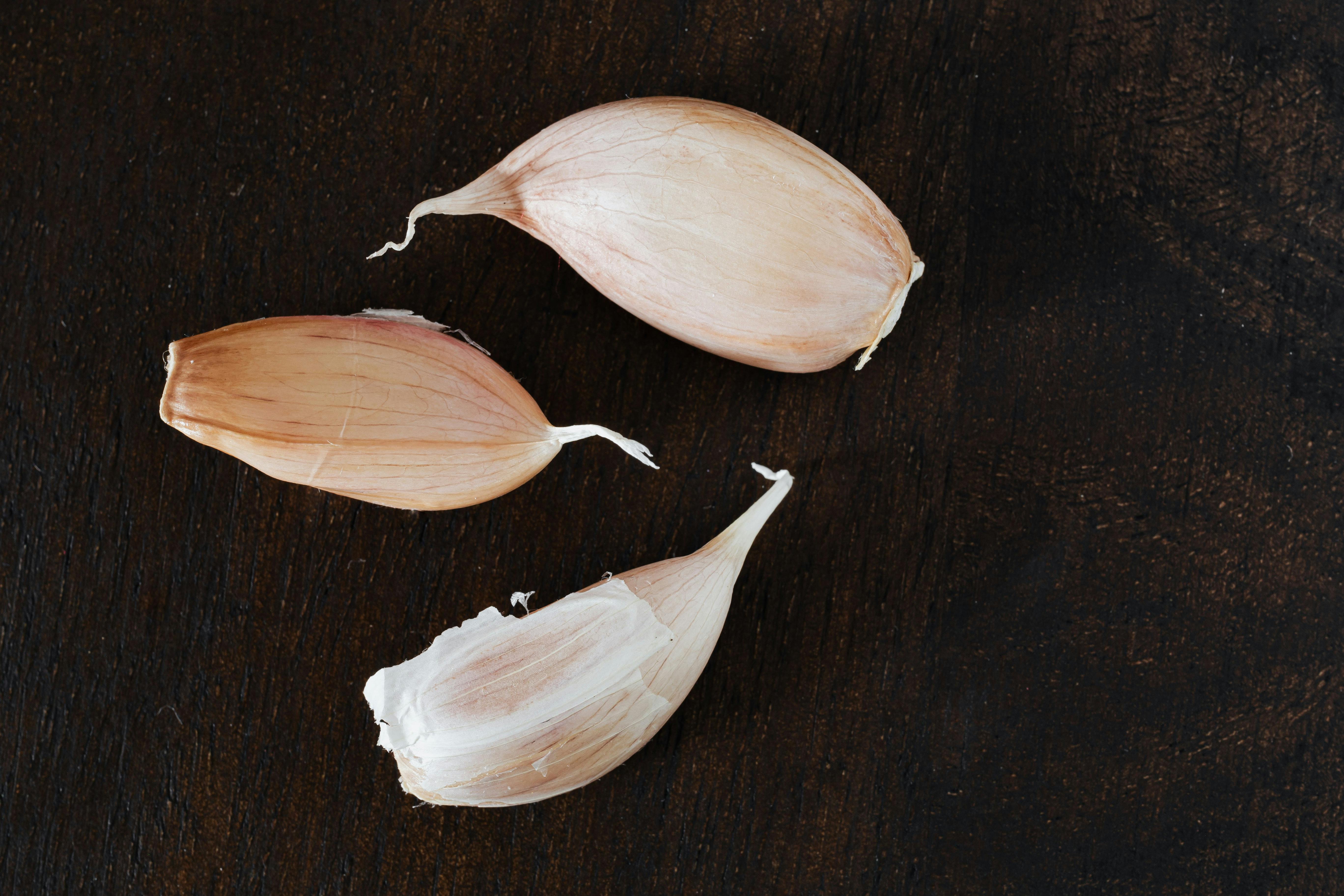 set of whole fresh cloves of garlic arranged on wooden tabletop in kitchen