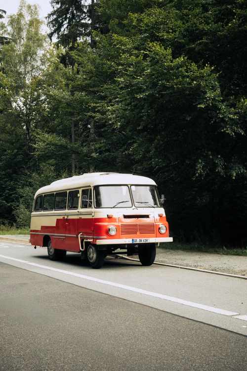 Free A classic red and white vintage bus travels along a scenic road in Zittauer Gebirge, Germany. Stock Photo