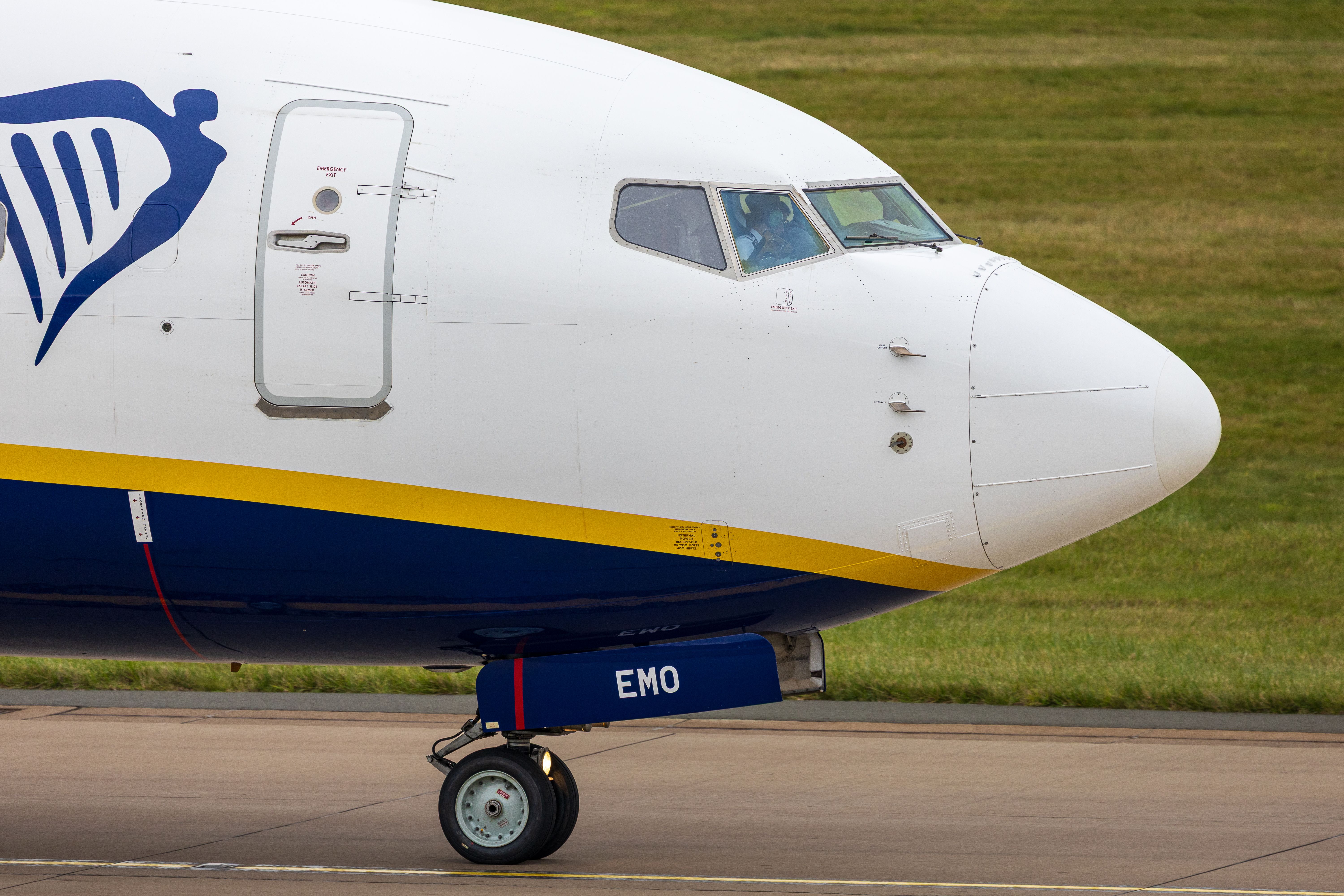 Close-up of a commercial airplane taxiing on a runway in Scotland, showcasing its landing gear and fuselage.