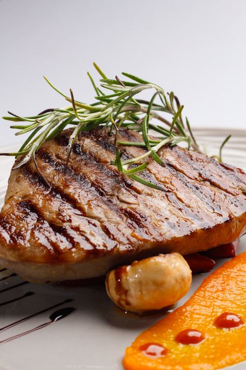 Free Juicy grilled steak garnished with rosemary and served with vibrant orange puree. Stock Photo