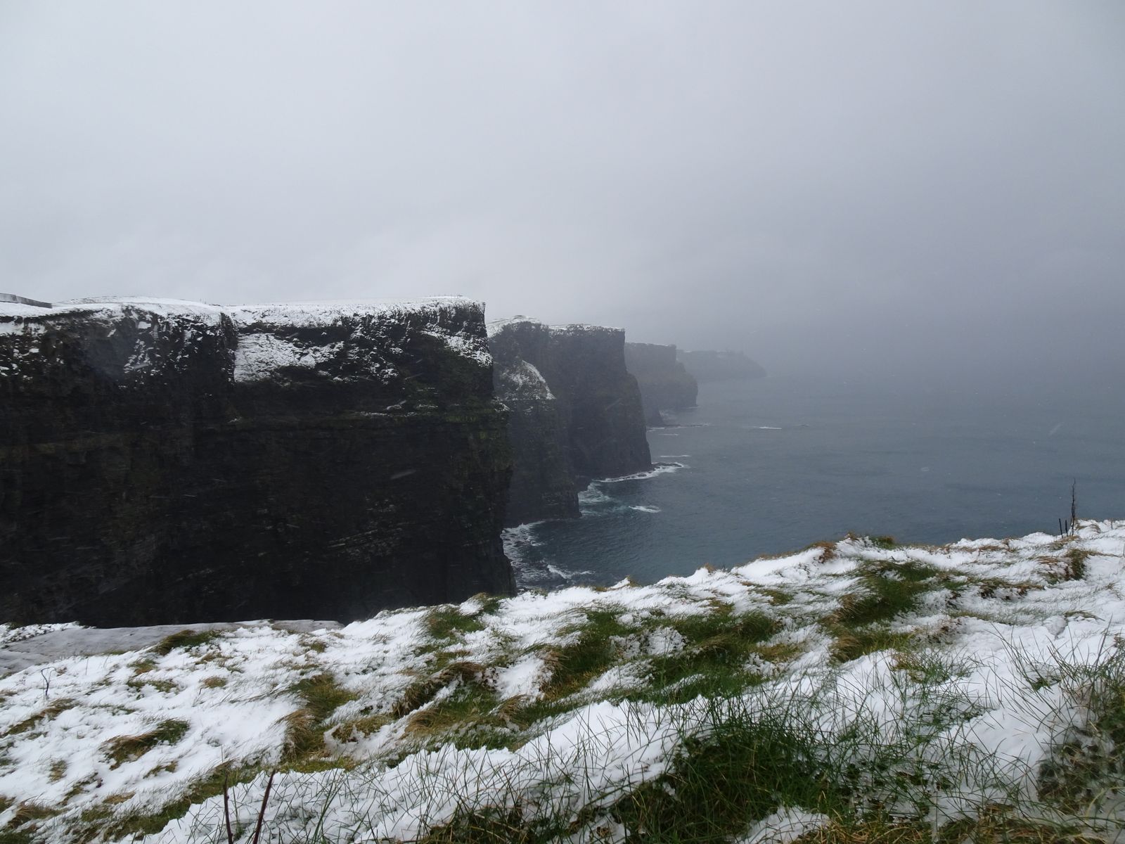 View of the snow-covered Cliffs of Moher under overcast skies in Ireland