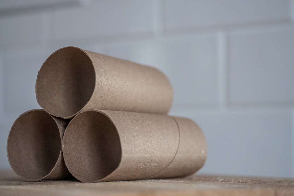 Free Closeup of stacked brown cardboard tubes of finished toilet paper placed on wooden table Stock Photo