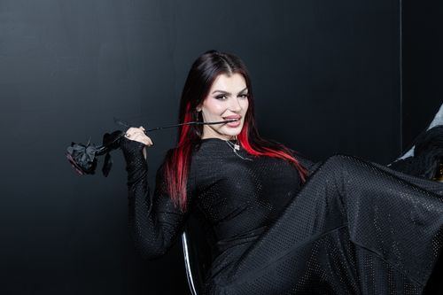 Free Stylish woman in black attire holding a black rose, striking a playful pose in a dark setting. Stock Photo